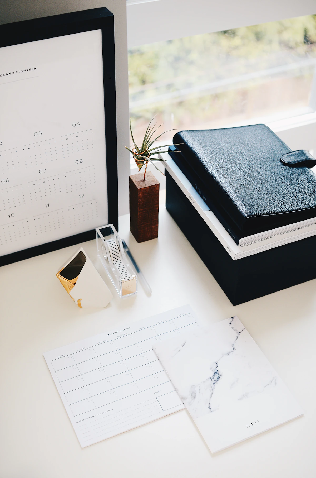 Desk calendar beside books and a small plant