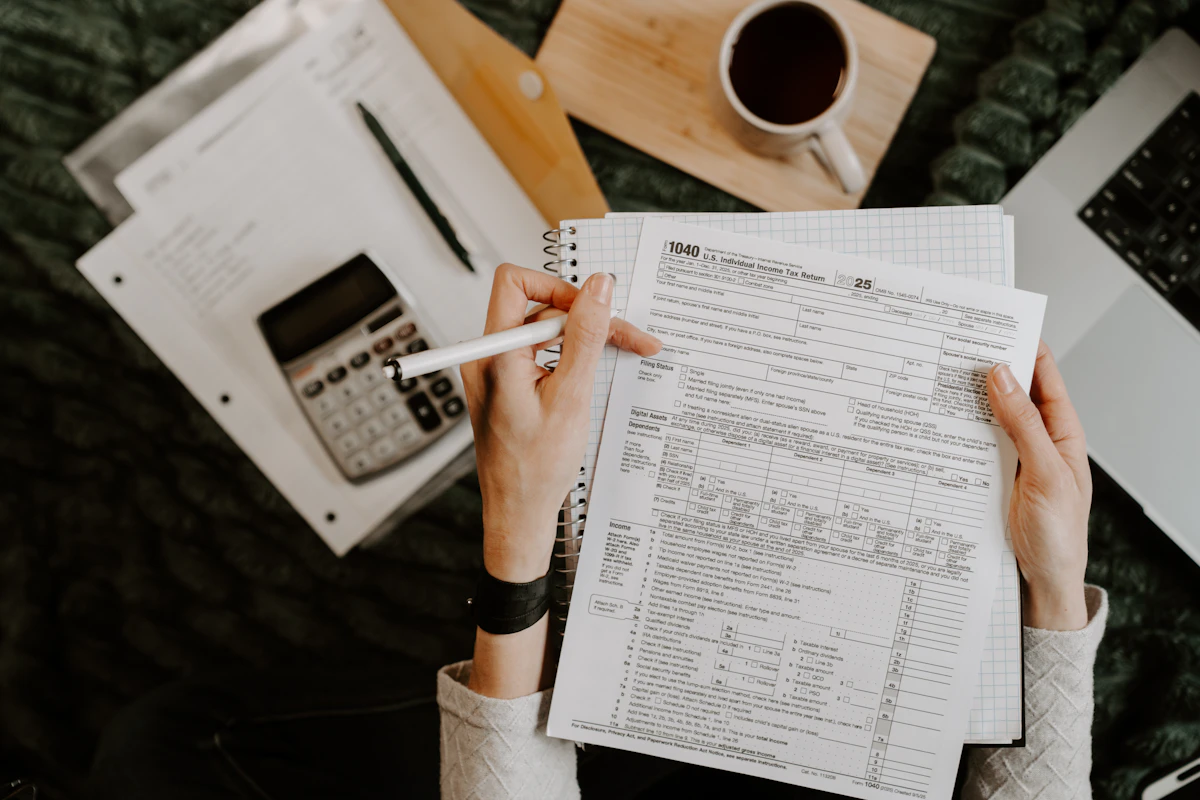 Hands reviewing documents beside a calculator and laptop